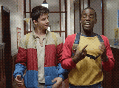Two Boys Are Walking Down A Hallway And One Of Them Is Wearing A Yellow Shirt GIF