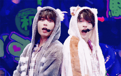 Two Boys In Furry Hooded Jackets Back To Back GIF