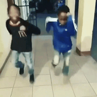 Two Boys Running Down Hallway With Faces Covered GIF
