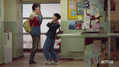 Two Boys Standing In Hallway Next To Quiz Bulletin Board GIF