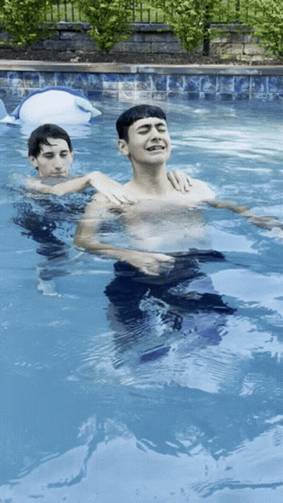 Two Boys Swimming, One Laughing In Pool GIF