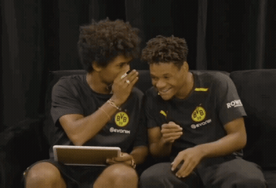 Two Boys Wearing Bvb Shirts Are Sitting On A Couch Laughing GIF