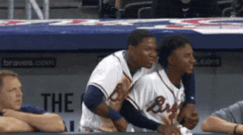 Two Braves Players Are Hugging Each Other In A Dugout GIF