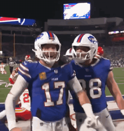 Two Buffalo Bills Players Are Standing On The Field GIF