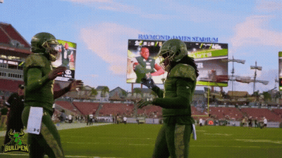 Two Bullpen Football Players Shake Hands In Front Of Raymond James Stadium Billboard GIF