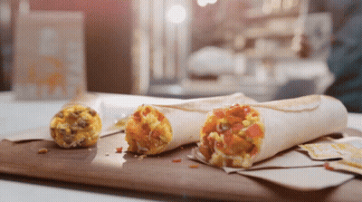Two Burritos Are Sitting On A Wooden Cutting Board Next To A Smaller Burrito GIF
