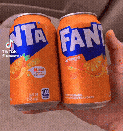 Two Cans Of Fanta Orange Soda Held In Hand GIF