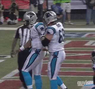 Two Carolina Panthers Football Players Are Hugging Each Other On The Field . GIF