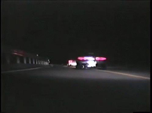 Two Cars Are Driving Down A Road At Night And One Has A License Plate That Starts With The Letter A GIF