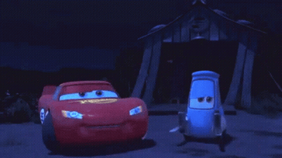 Two Cars Are Standing Next To Each Other In Front Of A Building At Night . GIF