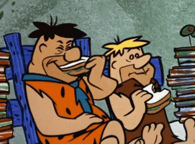 Two Cartoon Characters Eating Sandwiches Next To A Pile Of Books GIF