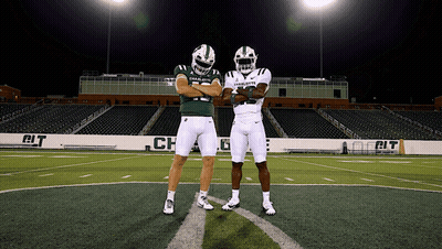 Two Charlotte Football Players Standing On A Field GIF