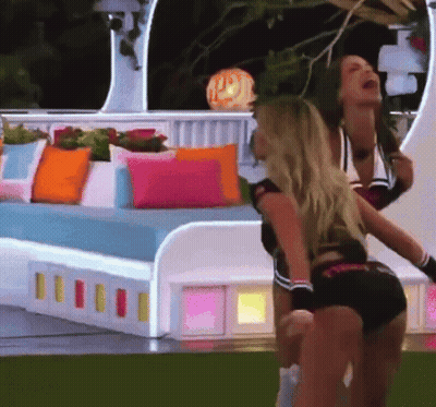 Two Cheerleaders In Front Of Bed With Pillows GIF