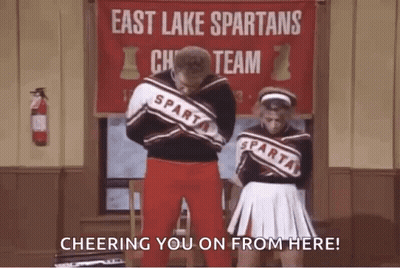 Two Cheerleaders In Front Of East Lake Spartans Cheer Team Banner GIF