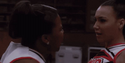Two Cheerleaders Looking At Each Other, One In UCLA Shirt GIF