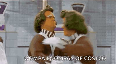 Two Chocolate Men Are Hugging Each Other In A Kitchen And The Words Oompa Loompas Of Costco Are Visible . GIF