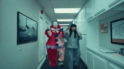 Two Clowns Are Running Down A Hallway With A Sign On The Wall That Says ' A ' GIF