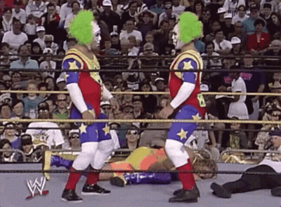 Two Clowns Are Standing In A Wrestling Ring . GIF