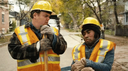 Two Construction Workers In Hard Hats And Vests GIF