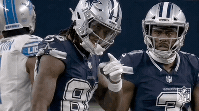Two Cowboys Football Players Are Standing Next To Each Other On The Field And Pointing At Each Other . GIF