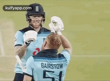 Two Cricket Players Are Shaking Hands On The Field . GIF