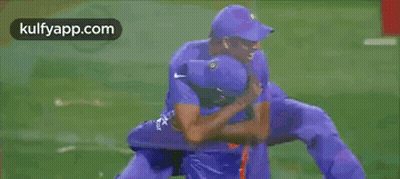 Two Cricket Players Hugging Each Other On A Field GIF