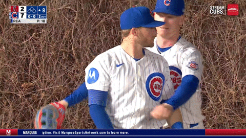 Two Cubs Baseball Players Are Hugging Each Other In Front Of A Scoreboard That Says Stream Cubs GIF