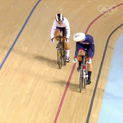 Two Cyclists Are Racing On A Track With The Olympic Rings On The Bottom GIF