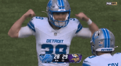 Two Detroit Football Players Flexing Muscles In Front Of Scoreboard GIF