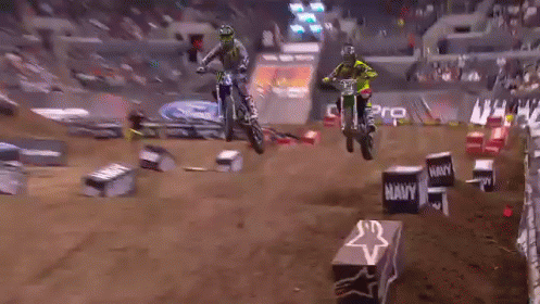 Two Dirt Bike Riders Are Jumping Over Boxes That Say Navy GIF