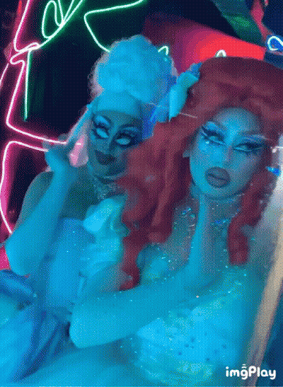 Two Drag Queens Posing With Neon Sign Saying Imgplay GIF