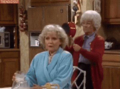 Two Elderly Women Are Sitting At A Table In A Kitchen . One Of The Women Is Wearing A Bathrobe . GIF