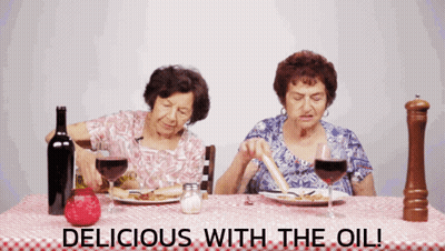 Two Elderly Women Sitting At A Table With The Words " Delicious With The Oil " GIF