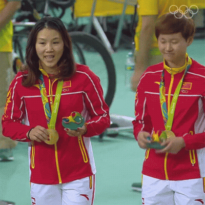 Two Female Athletes From China Are Holding Their Medals GIF