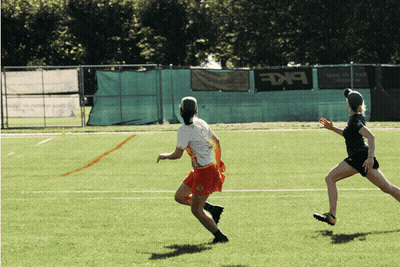 Two Female Athletes Running On Field With BKF Banner GIF