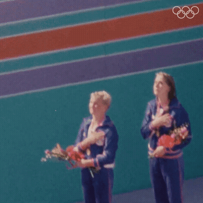 Two Female Athletes Standing With Hands On Chest GIF