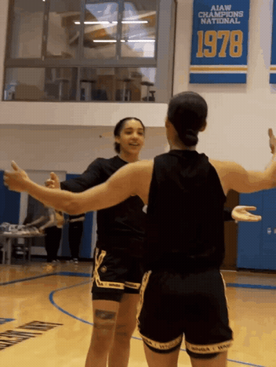 Two Female Basketball Players Hugging In Front Of AIAW Champions National 1978 Banner GIF