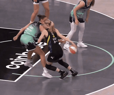 Two Female Basketball Players On Court With Coin GIF