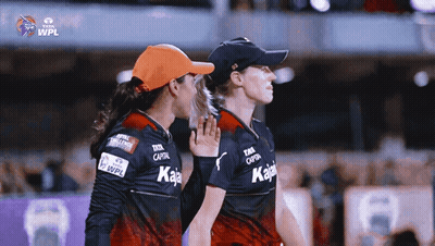 Two Female Cricket Players Standing Next To Each Other With The Wpl Logo On The Bottom GIF