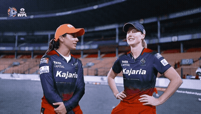 Two Female Cricket Players Wearing Kajaria Jerseys Stand Next To Each Other GIF