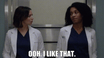 Two Female Doctors Are Standing Next To Each Other In A Hallway And One Of Them Is Talking . GIF