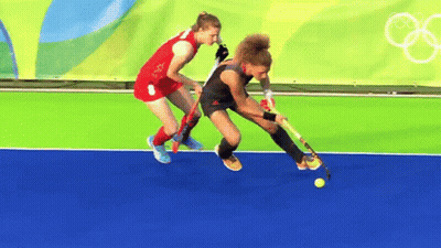 Two Female Field Hockey Players Are Playing On A Field GIF