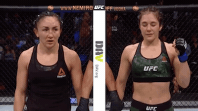 Two Female Fighters Are Standing Next To Each Other In A Cage . GIF