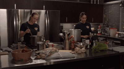 Two Female Firefighters Cooking In Kitchen GIF