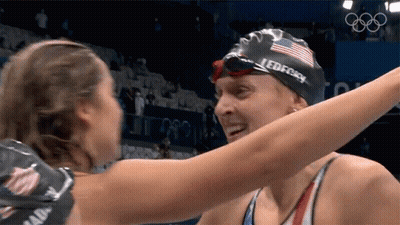 Two Female Swimmers Hugging One With Speedo Cap GIF