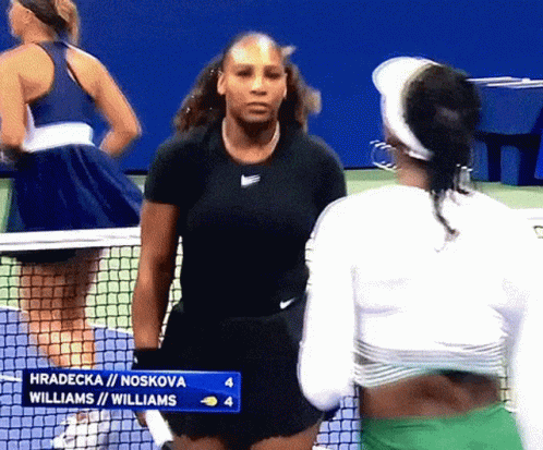 Two Female Tennis Players Are Standing Next To Each Other On A Tennis Court GIF