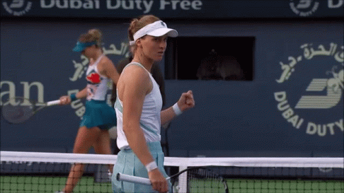 Two Female Tennis Players On A Court With A Dubai Duty Free Sign In The Background GIF