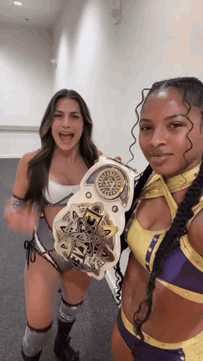 Two Female Wrestlers Are Posing For A Picture While Holding A Wwe Championship Belt . GIF