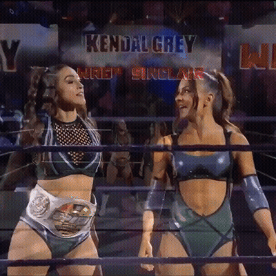 Two Female Wrestlers Are Standing In A Ring With The Name Kendal Grey Above Them GIF