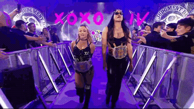 Two Female Wrestlers Are Walking Through A Tunnel With A Crowd Of People Behind Them . GIF